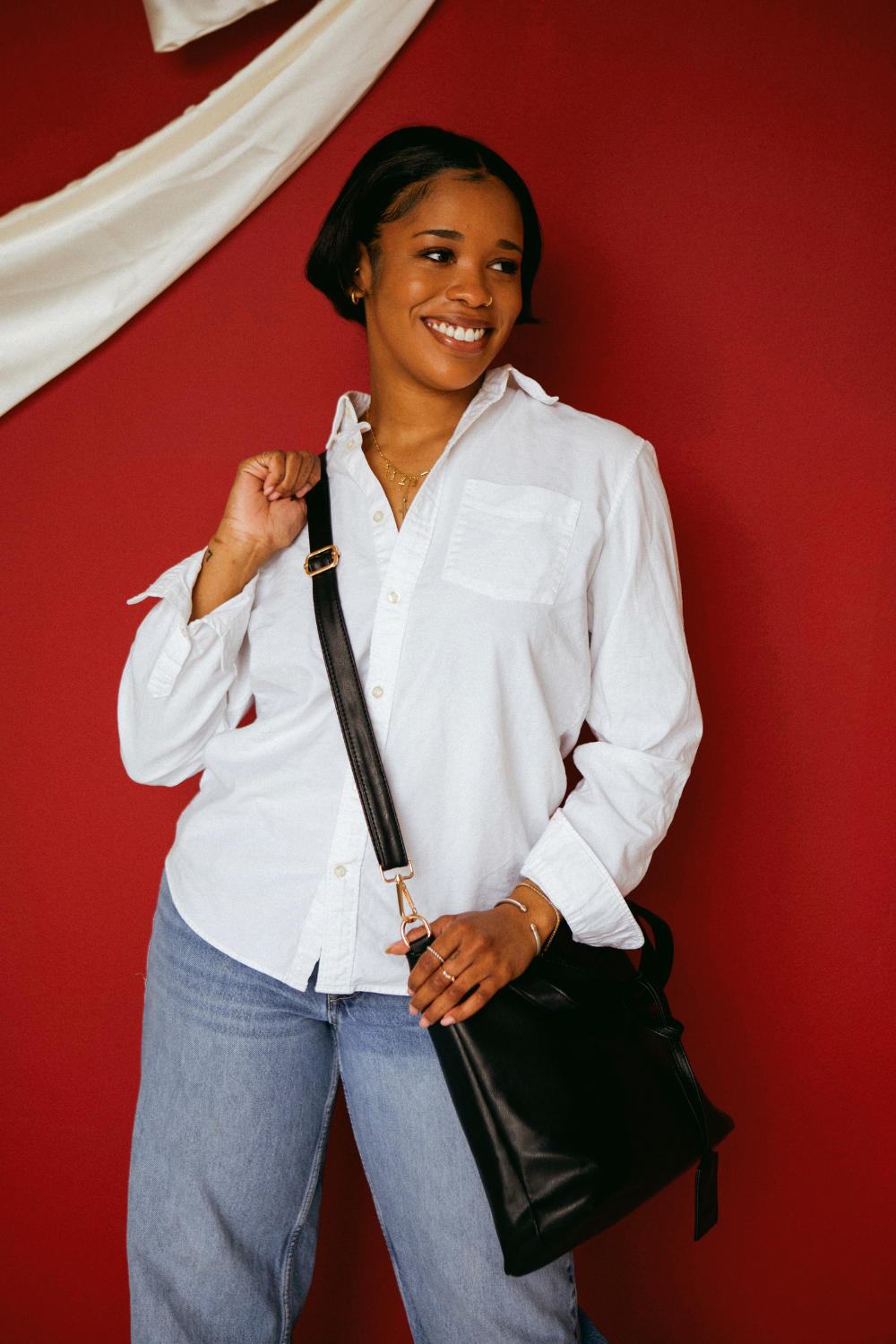 A woman wearing a white button up shirt with jeans and a black Drury Road Olivia Convertible Slouchy Tote Bag for Women across her body.