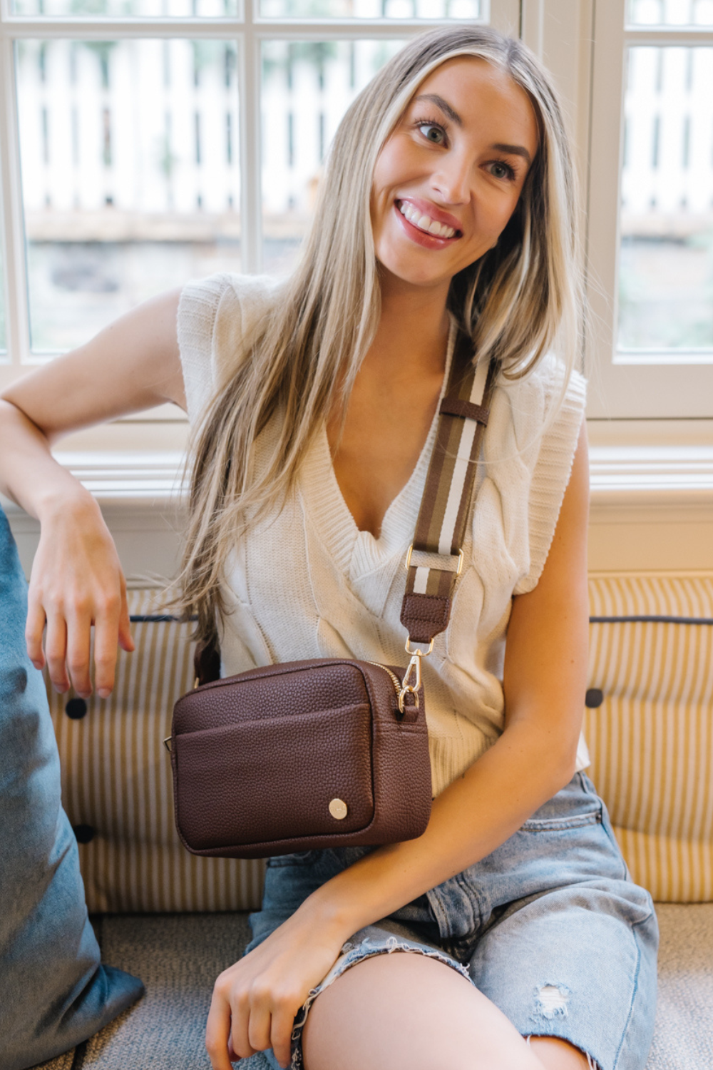 Woman wearing a brown Drury Road Willow Vegan Leather Convertible Crossbody Bag on a white background. 
