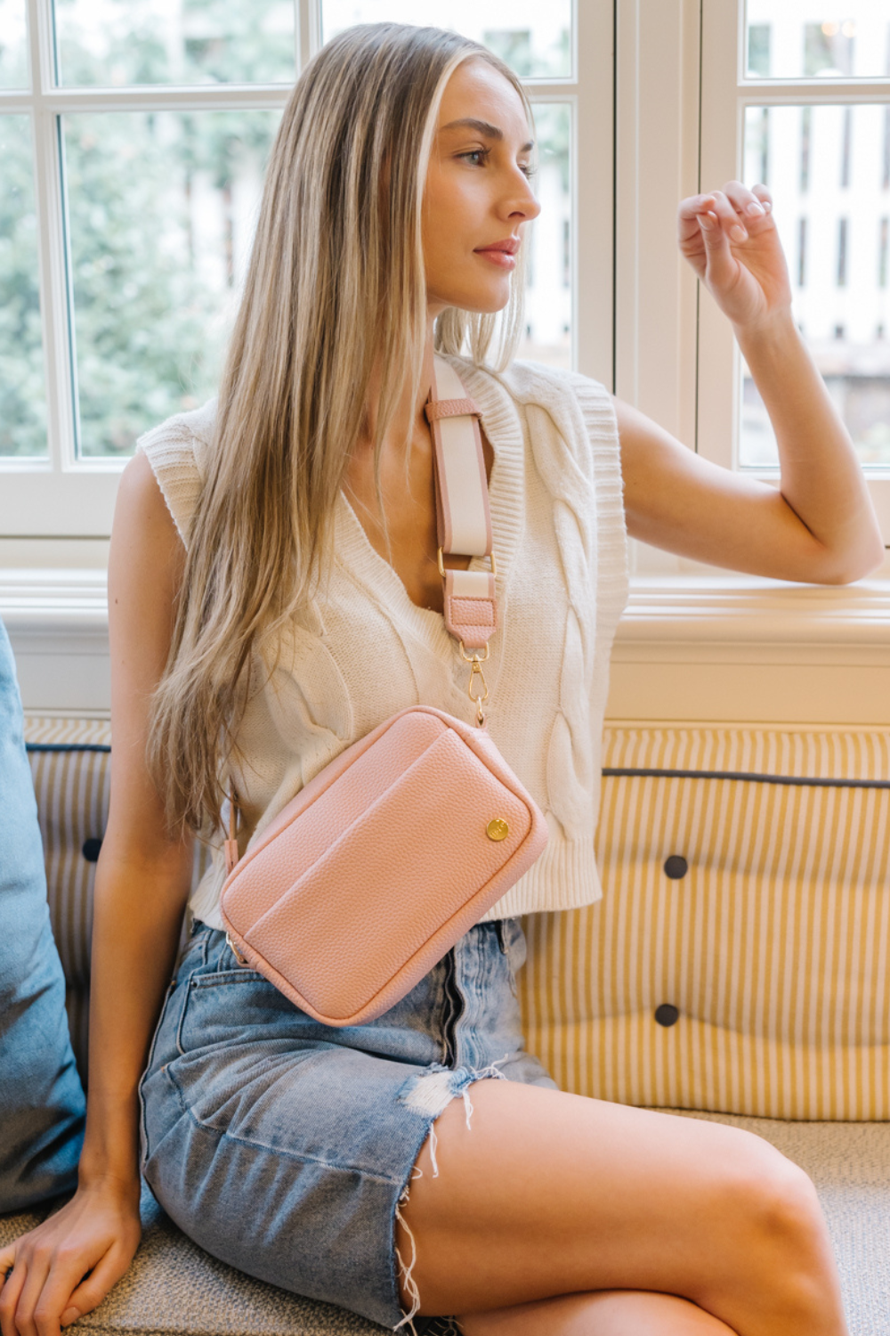 Woman wearing a pink Drury Road Willow Vegan Leather Convertible Crossbody Bag in front of a window.