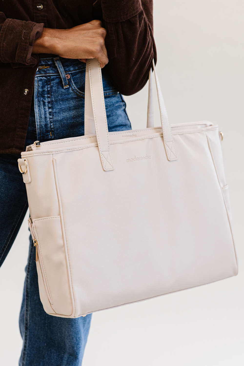 A woman holding a cream tote with the Drury Road logo on the front.