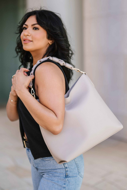 Woman wearing a beige Drury Road Sawyer Convertible Slouchy Tote Bag for Women with a vegan leather braided shoulder strap against a neutral background. 