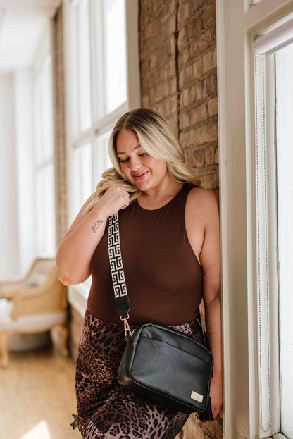 A blonde woman modeling a Drury Road Black Alice Crossbody Bag with abstract printed strap.