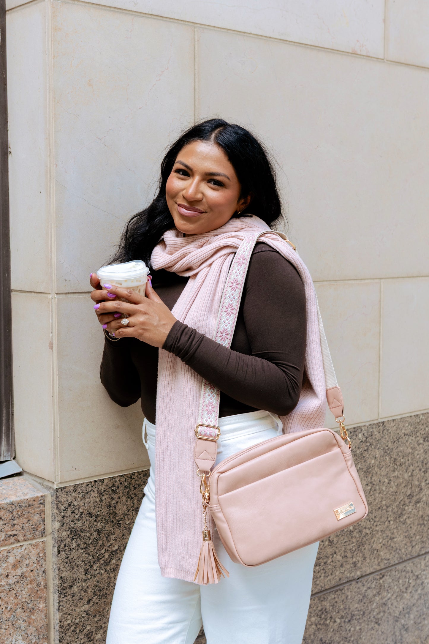 A olive skinned, dark haired woman modeling a dusty blush colored Drury Road Alice Crossbody bag. 