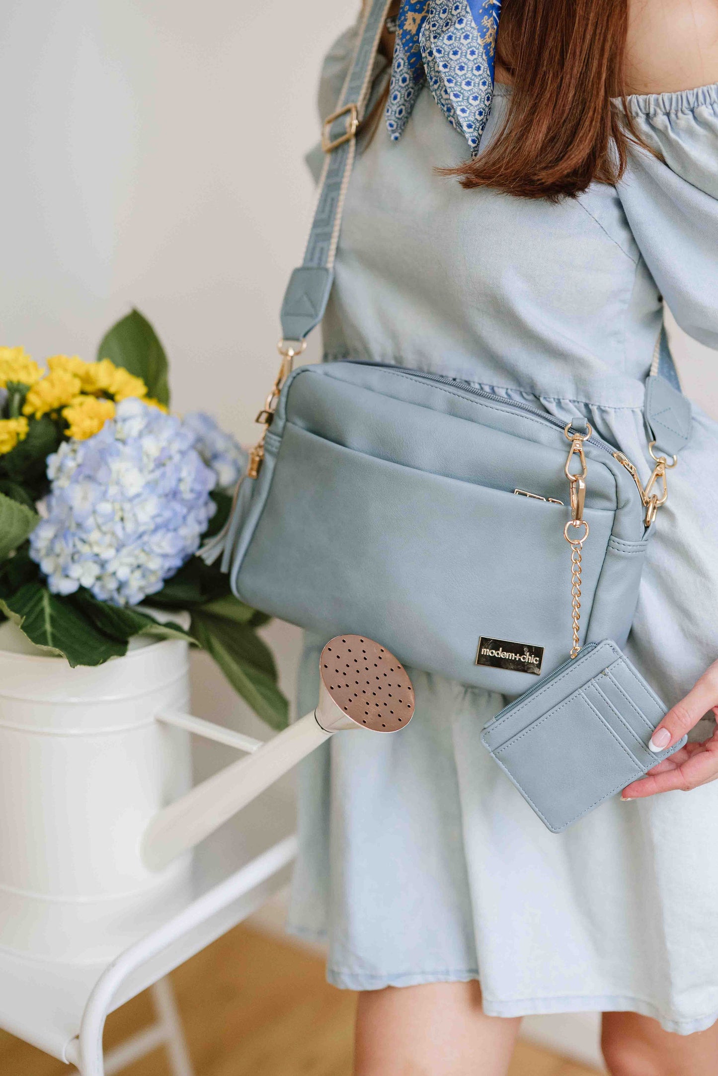 A red-haired woman modeling a Drury Road Dusty Blue Alice Crossbody Bag: Vegan Leather Bag, Key Leash & Wallet