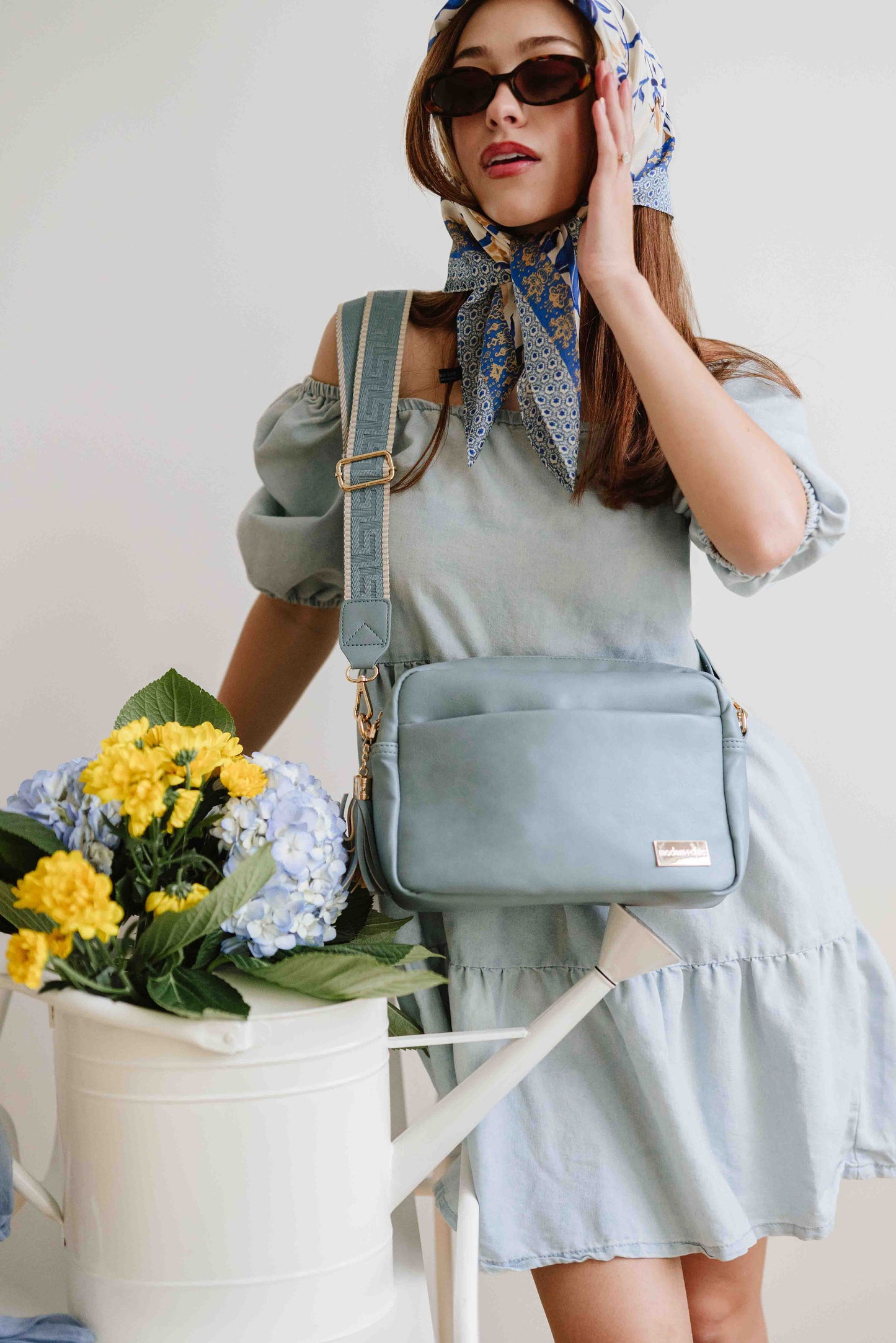 A red-haired woman modeling a Drury Road Dusty Blue Alice Crossbody Bag: Vegan Leather Bag, Key Leash & Wallet