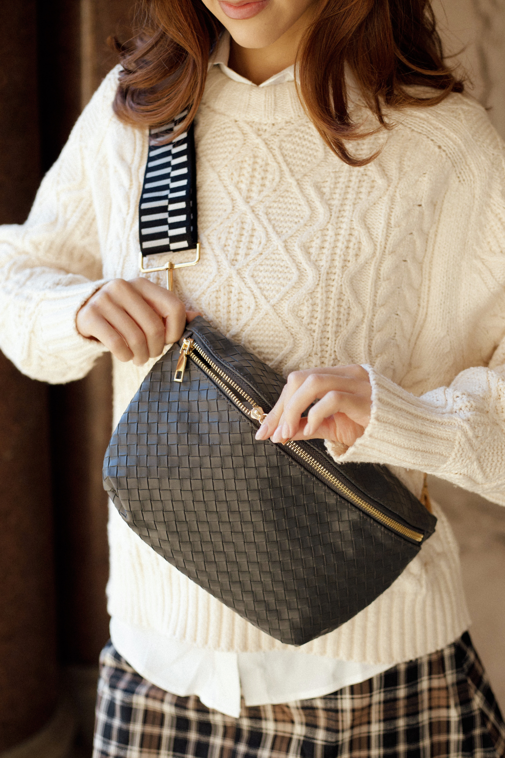 Woman unzipping a gold zipper on a black faux quilted Drury Road Rory Oversized Belt Bag for Women – Vegan Leather