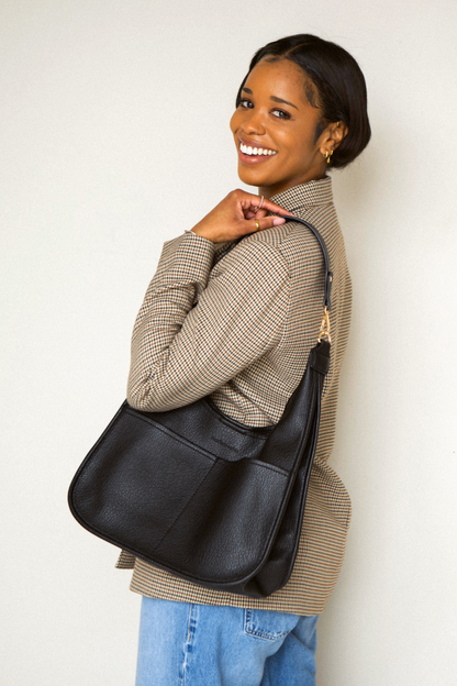 Woman holding a black  Drury Road Clara Vegan Leather Slouchy Tote Bag for Women on a white background. 