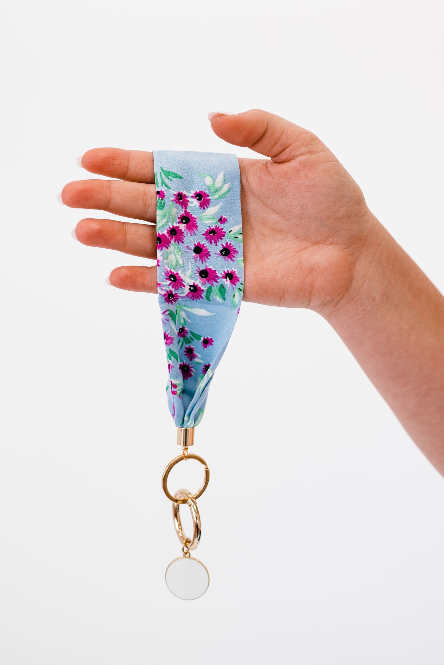 A hand holding Drury Road Luna Fabric Keychain Bracelet for Women in front of a white background.