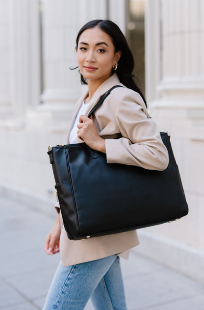A woman wearing a black tote on her shoulder.