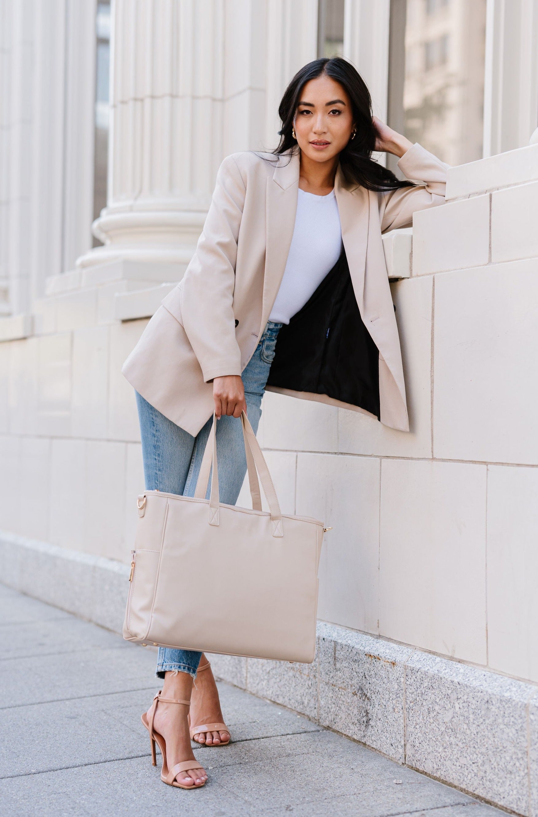 A woman holding a cream tote.