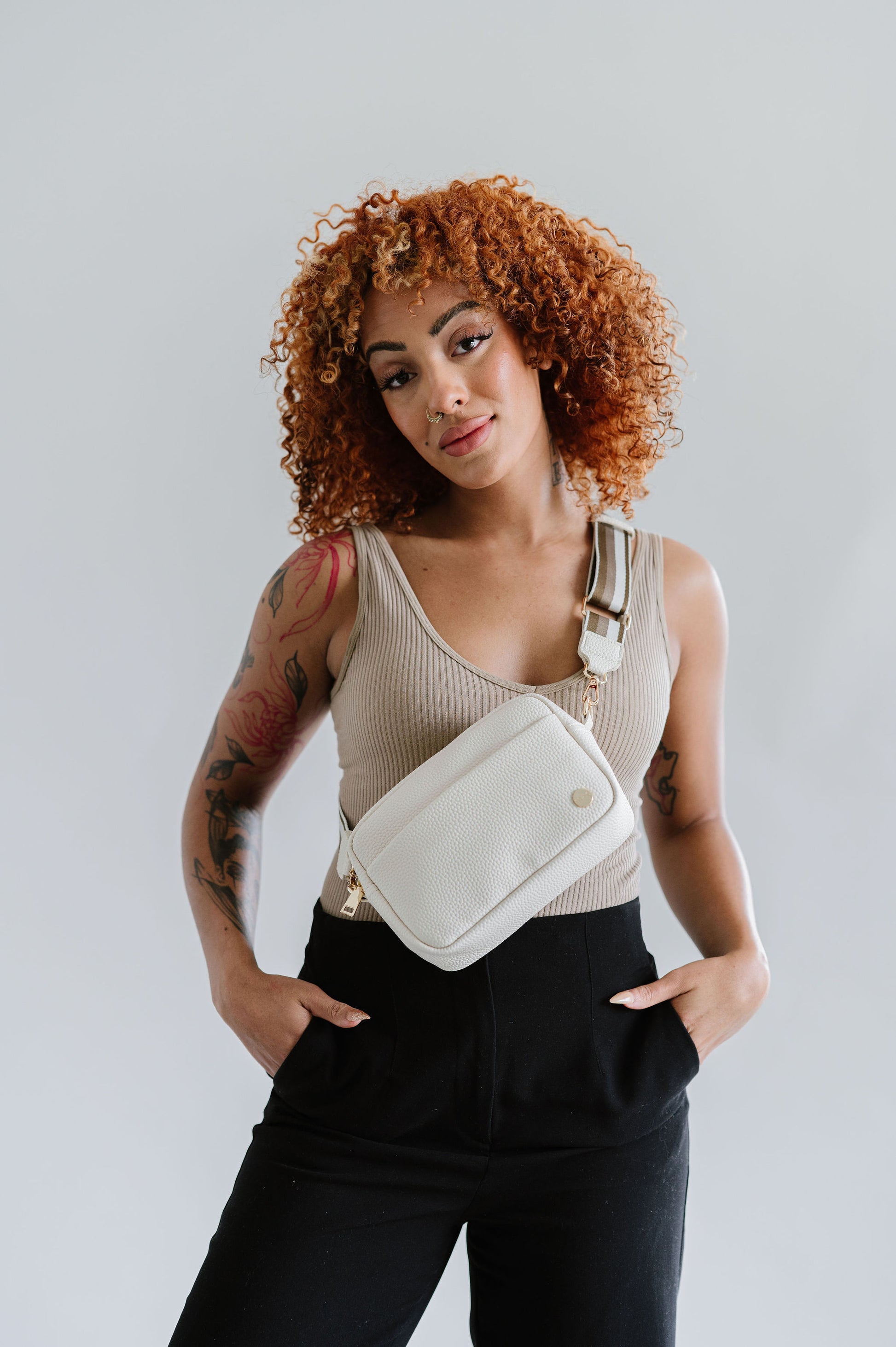 Woman wearing a cream Drury Road Willow Vegan Leather Convertible Crossbody Bag on a white background. 