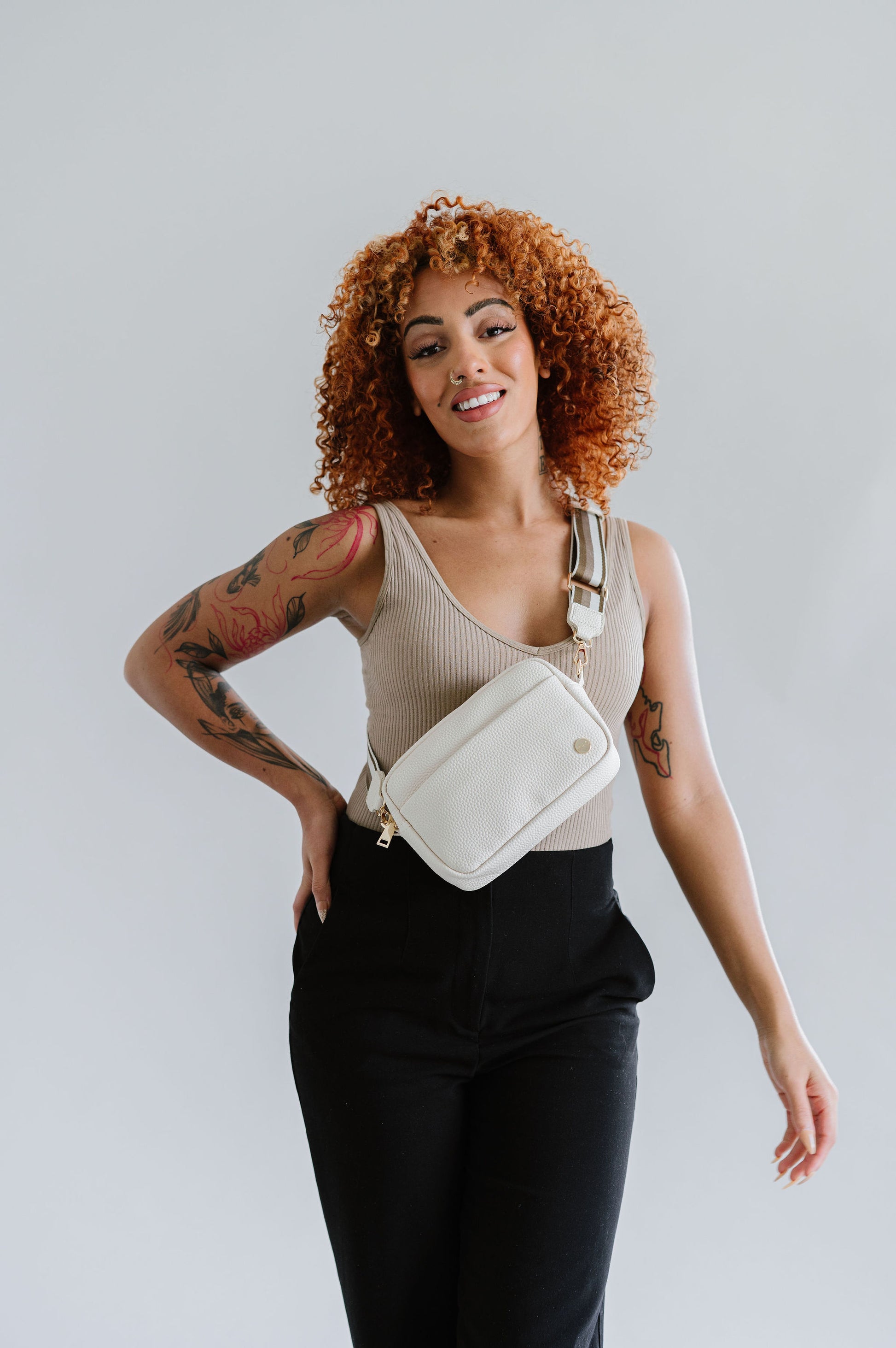 Woman wearing a cream Drury Road Willow Vegan Leather Convertible Crossbody Bag on a white background. 