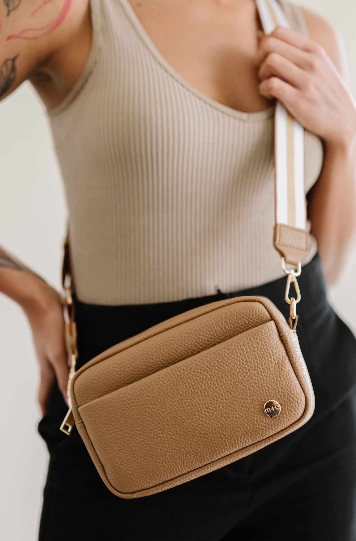 Woman wearing a beige Drury Road Willow Vegan Leather Convertible Crossbody Bag on a white background. 