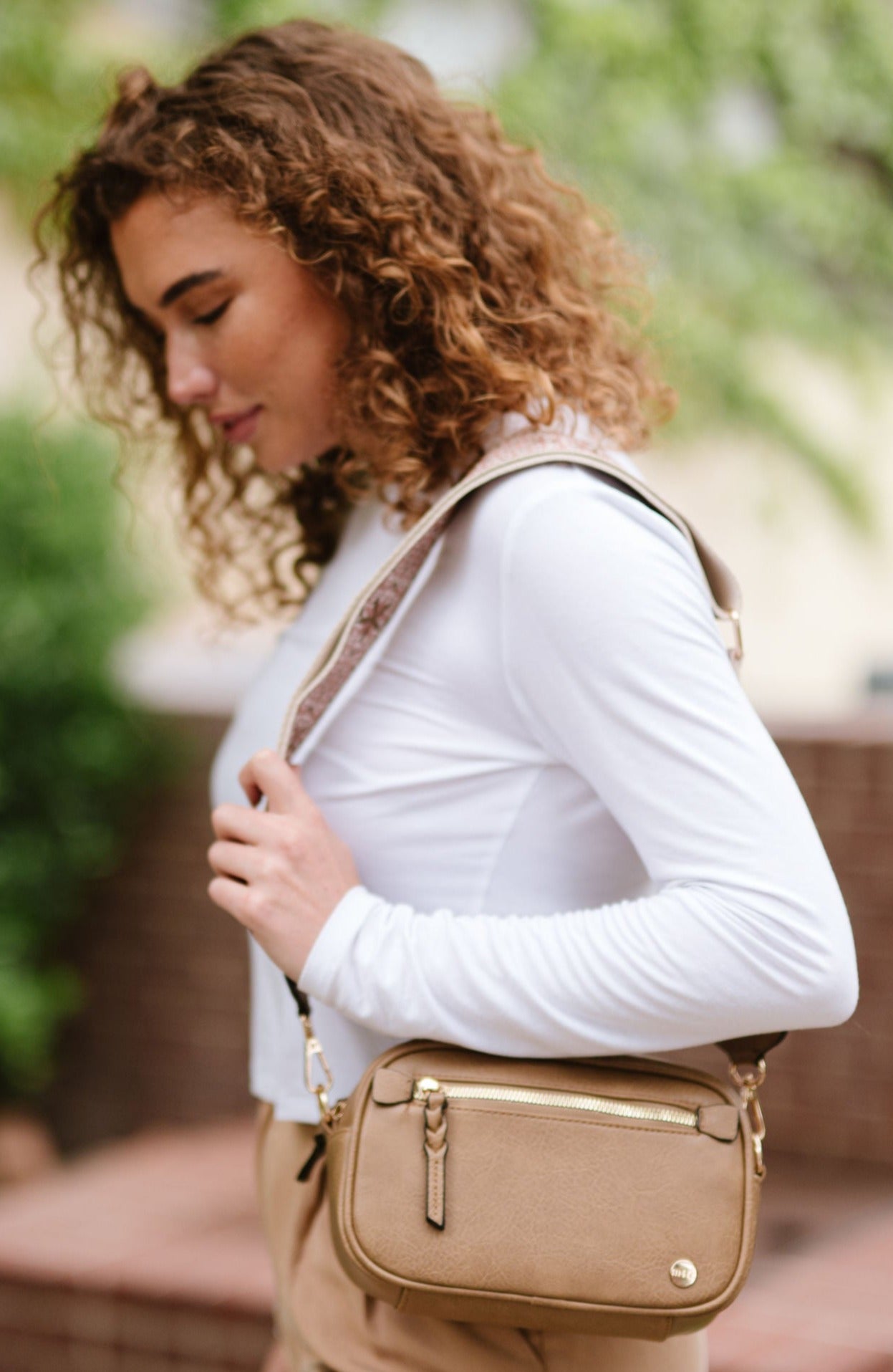 Woman wearing white shirt, tan pants and a Drury Road Gentry Vegan Leather Crossbody Bag in tan.