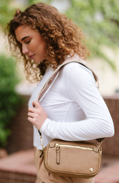 Woman wearing white shirt, tan pants and a Drury Road Gentry Vegan Leather Crossbody Bag in tan.
