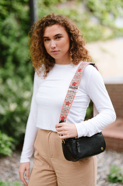 Woman wearing white shirt, tan pants and a Drury Road Gentry Vegan Leather Crossbody Bag in black.