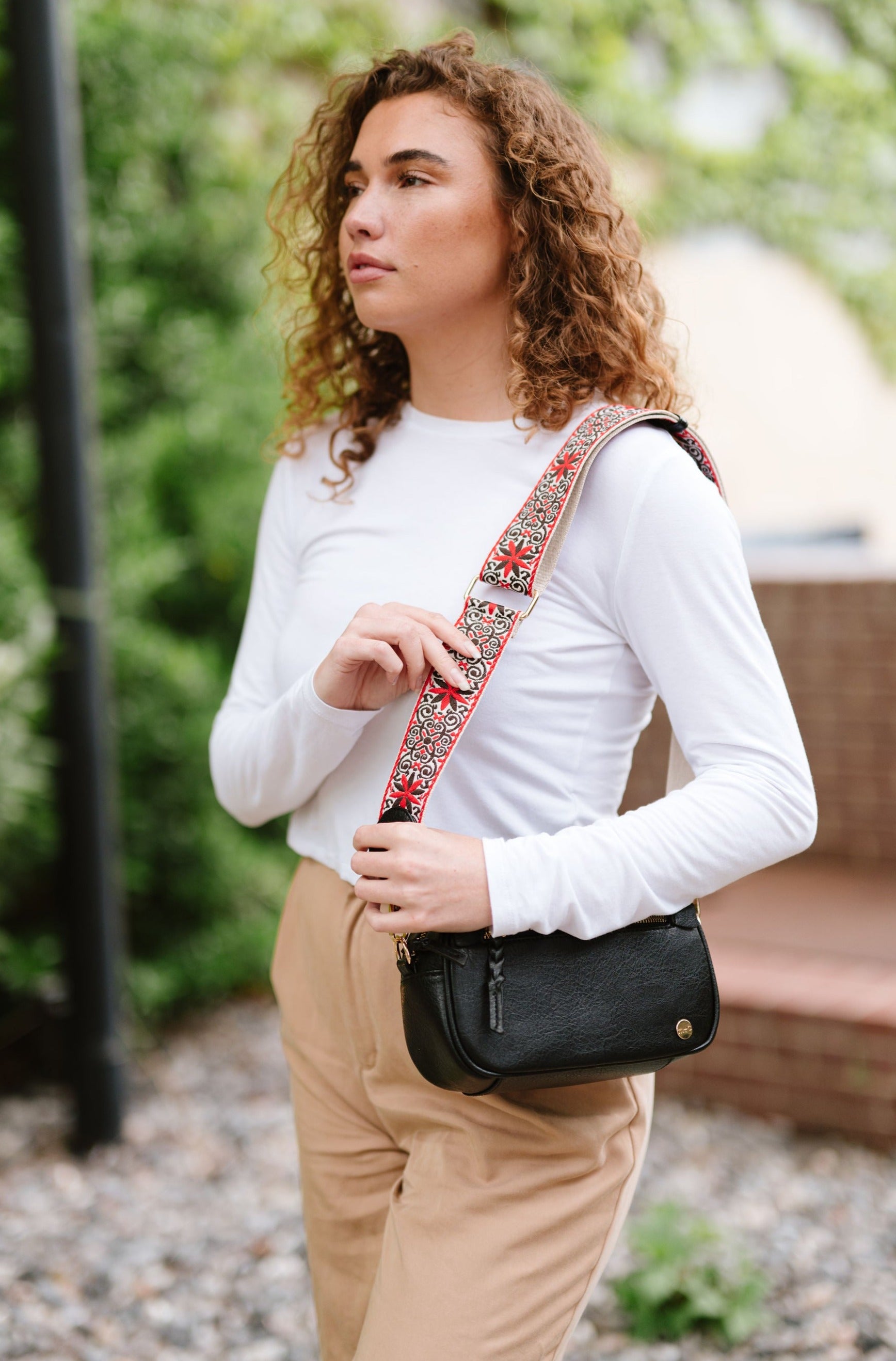 Woman wearing white shirt, tan pants and a Drury Road Gentry Vegan Leather Crossbody Bag in black.