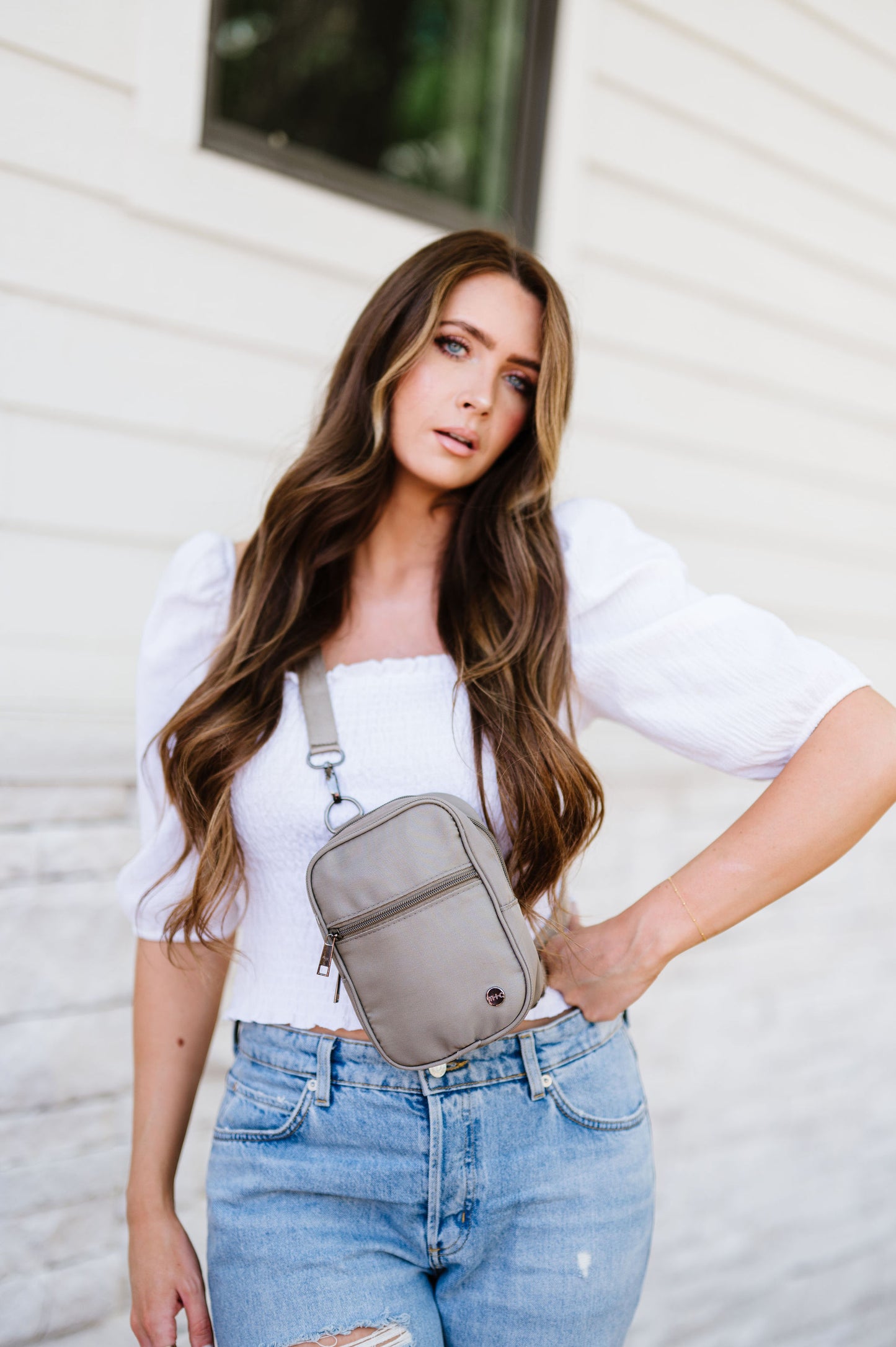 Woman wearing a white top, jeans and a grey Drury Road Lainey Convertible Crossbody Bag for Women crossbody.