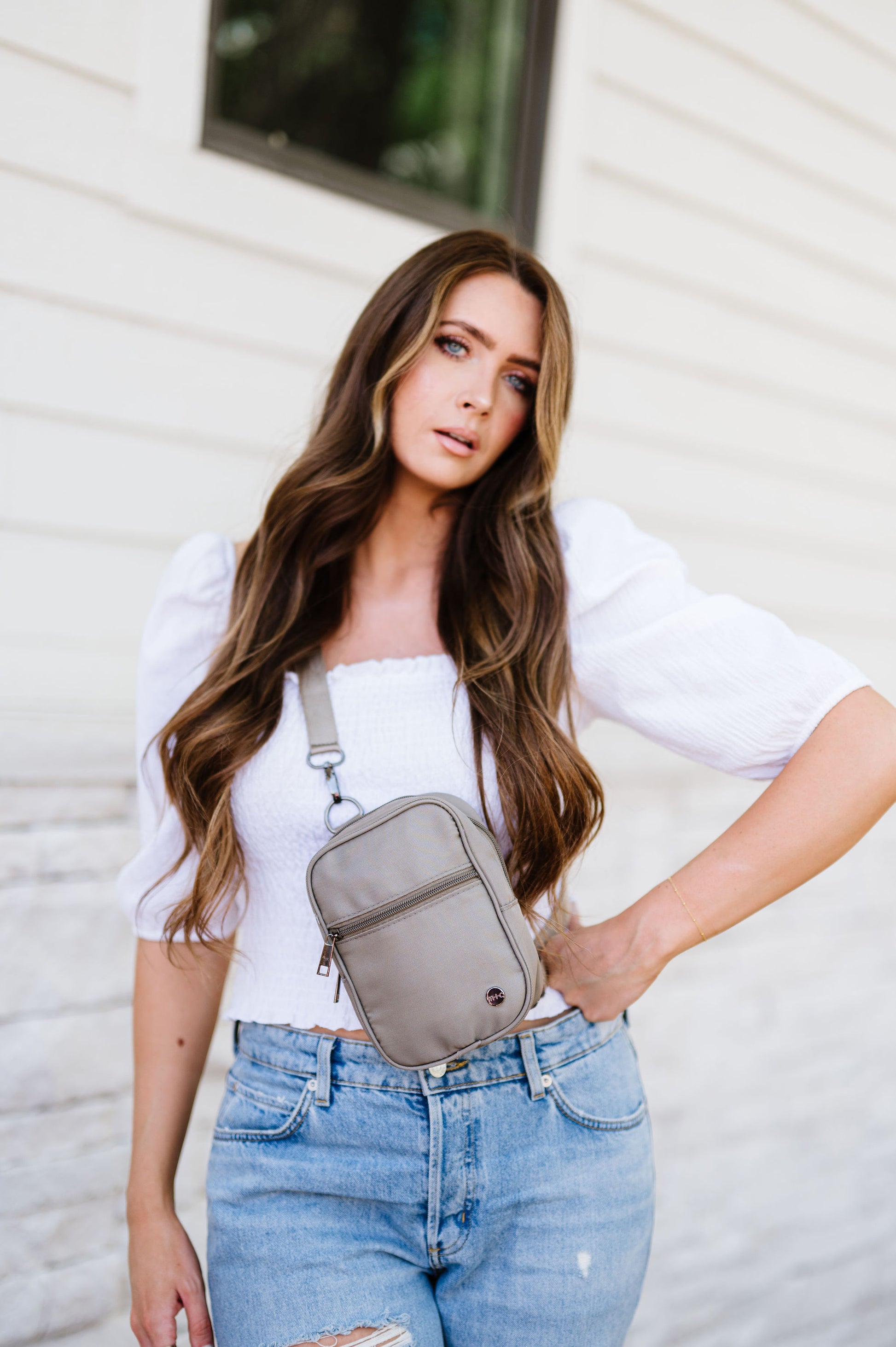 Woman wearing a white top, jeans and a grey Drury Road Lainey Convertible Crossbody Bag for Women crossbody.