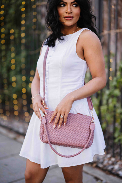 Woman in a white dress holding a pink Drury Road Elle Woven Crossbody Bag for Women outdoors.