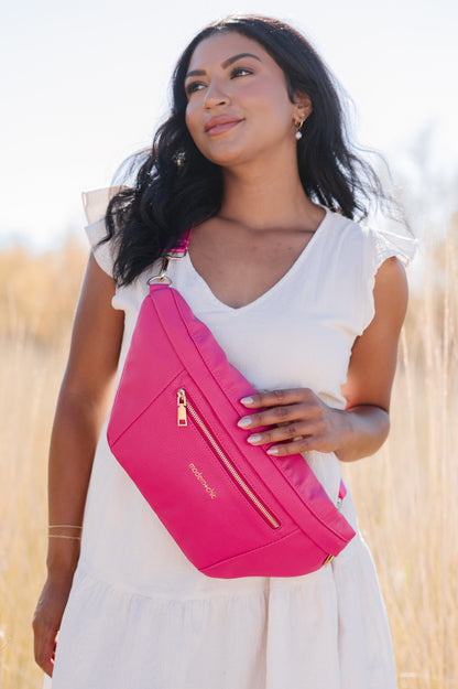 A woman wearing a white dress and a hot pink oversized Drury Road Presley Oversized Sling Bag for Women with gold hardware across her torso.