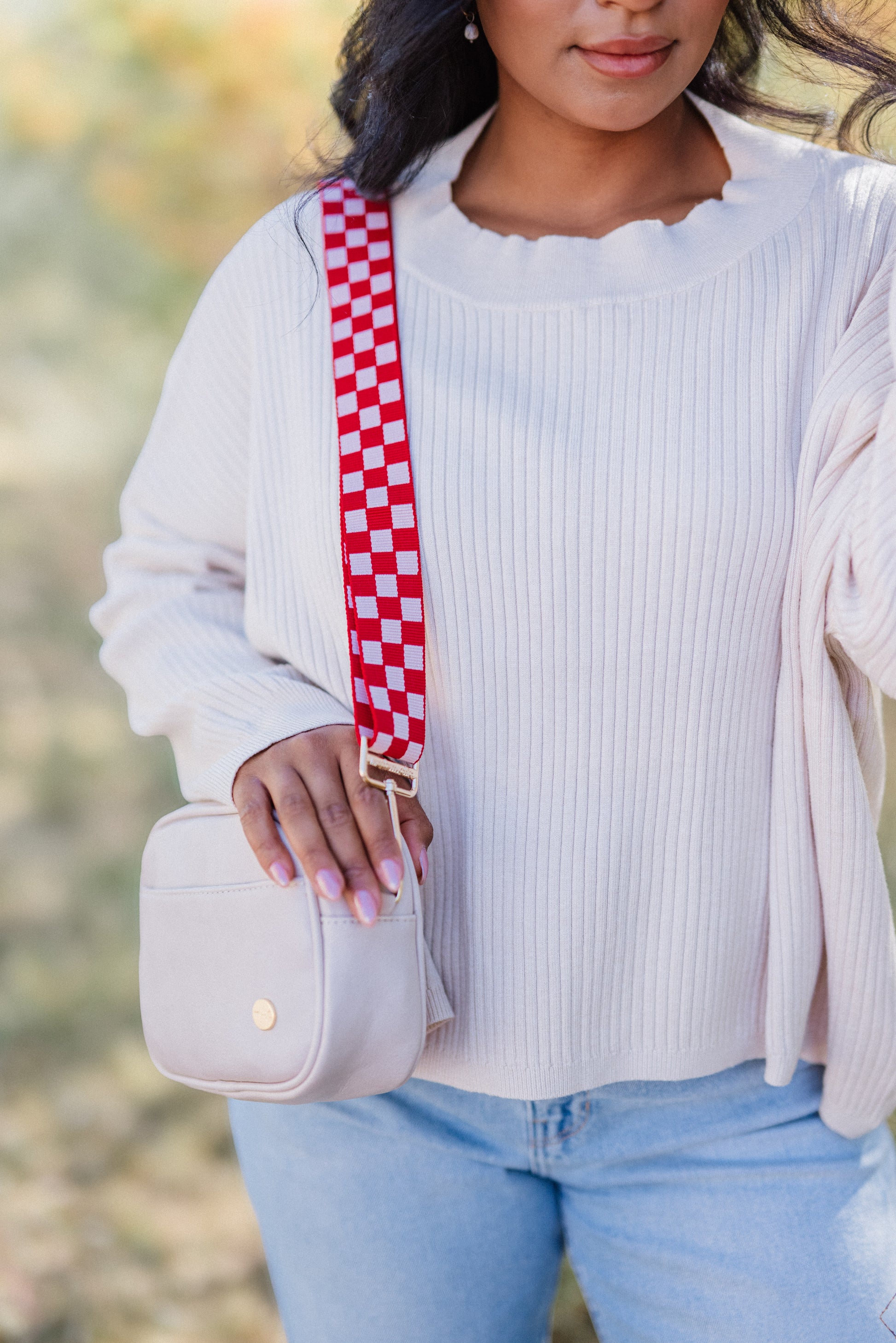 woman wearing a pale pink top and a Drury Road pale pink shoulder bag with a coordinating red and pink Drury Road Lizzie Checkered adjustable bag strap.
