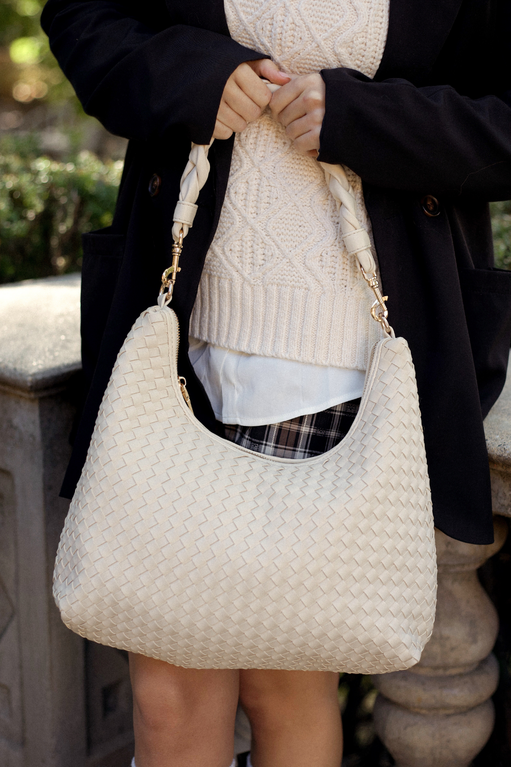 Person holding an ivory Drury Road Kelly Woven Convertible Crossbody Shoulder Bag outdoors.