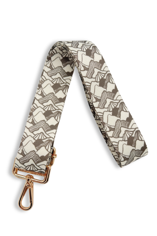 Patterned mountain range bag strap with gold hardware on a white background