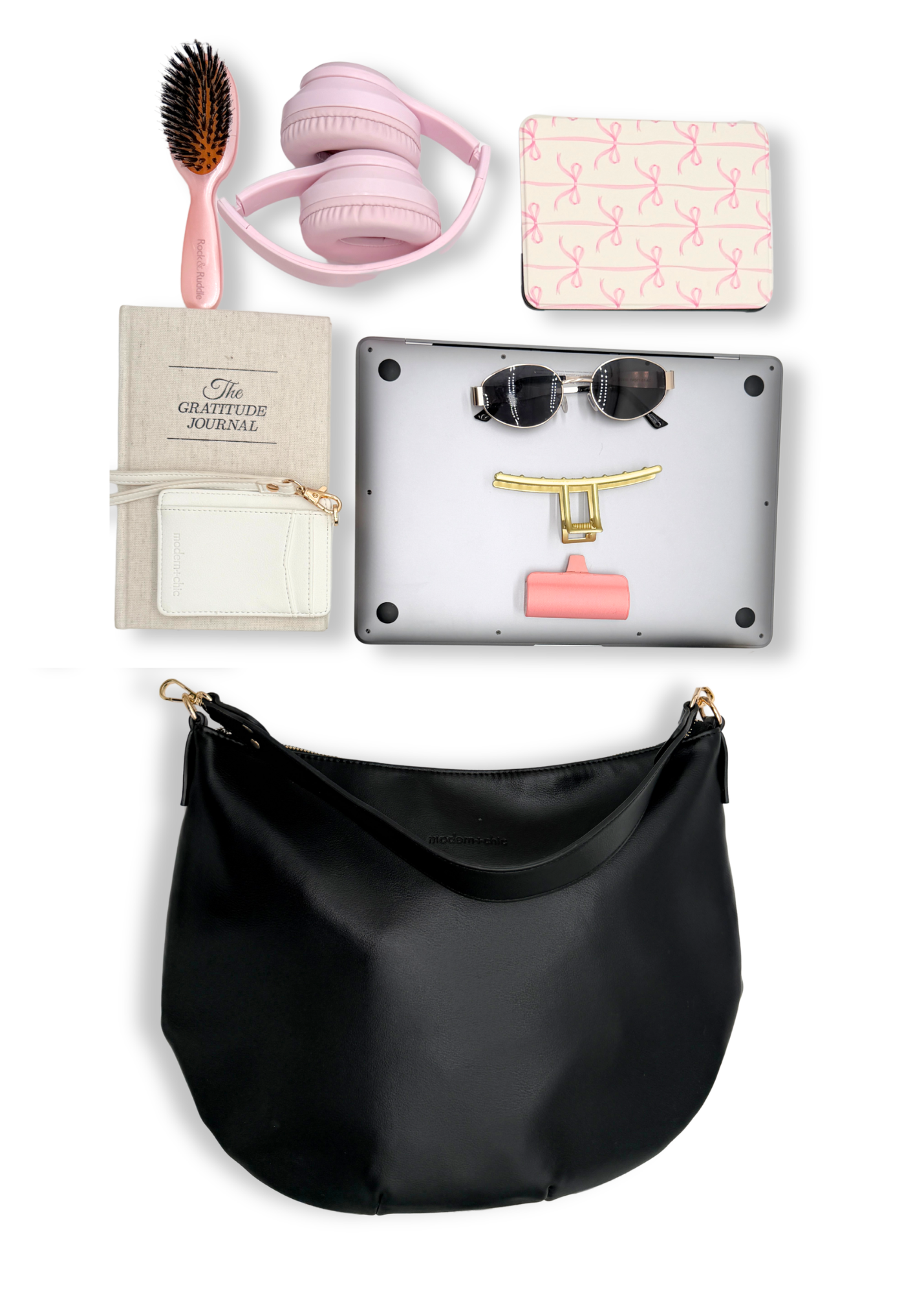A black vegan leather Drury Road Savannah Slouchy Tote on a white background with pink accessories including headphones, a hairbrush, and a small notebook on a white background.