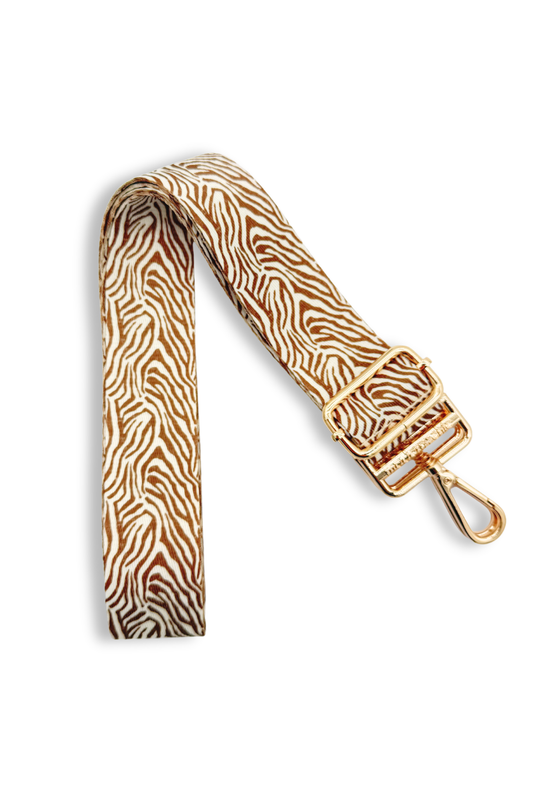 Zebra print bag strap with gold hardware on a white background