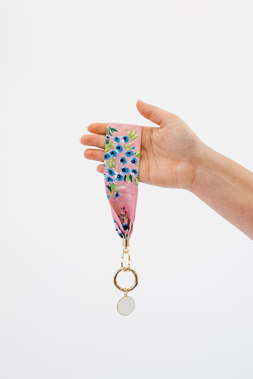 A hand holding Drury Road Luna Fabric Keychain Bracelet for Women in front of a white background.