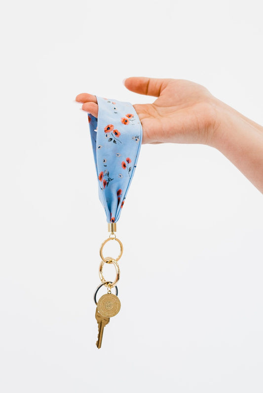 A hand holding Drury Road Luna Fabric Keychain Bracelet for Women in front of a white background.