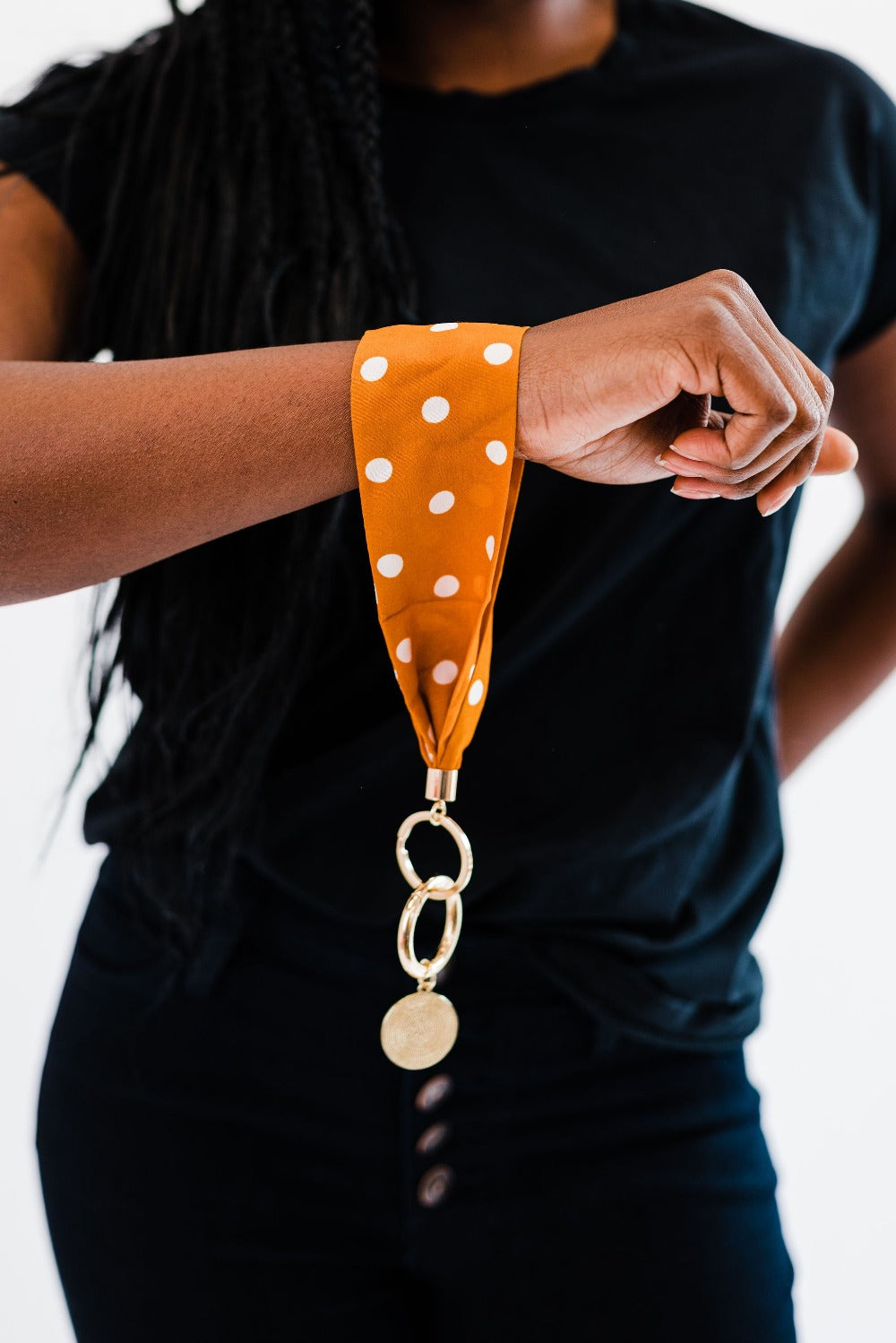 A woman wearing all black wearing an orange and white polka dot Drury Road Luna Fabric Keychain Bracelet for Women.