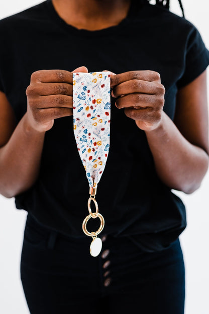 A woman wearing all black holding a Drury Road Luna Fabric Keychain Bracelet for Women. 