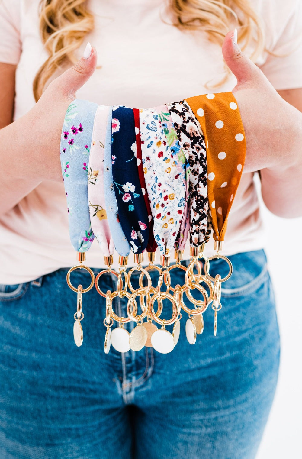 A person holding out Drury Road Luna Fabric Keychain Bracelets for Women-  showcasing various patterns and colors such as animal print, floral, dots, and plain colors.