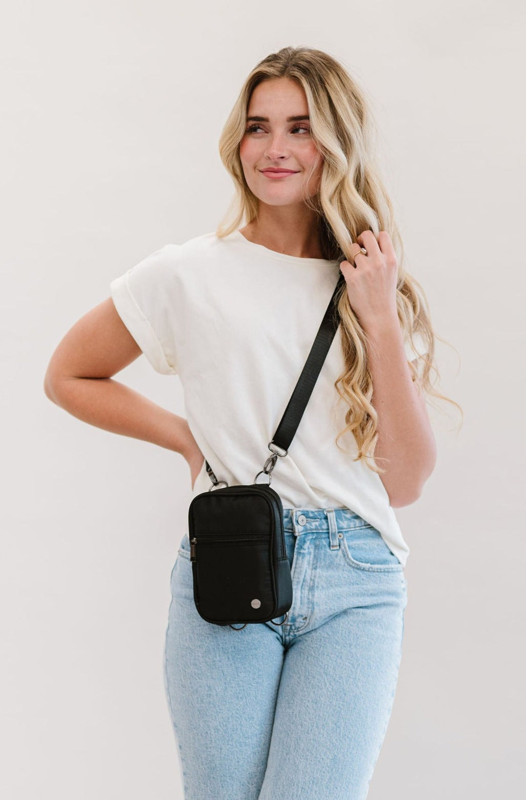 A woman wearing a black Drury Road Lainey Convertible Crossbody Bag for Women with a white top and jeans.
