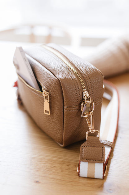 A beige Drury Road Willow Vegan Leather Convertible Crossbody Bag on a desk.
