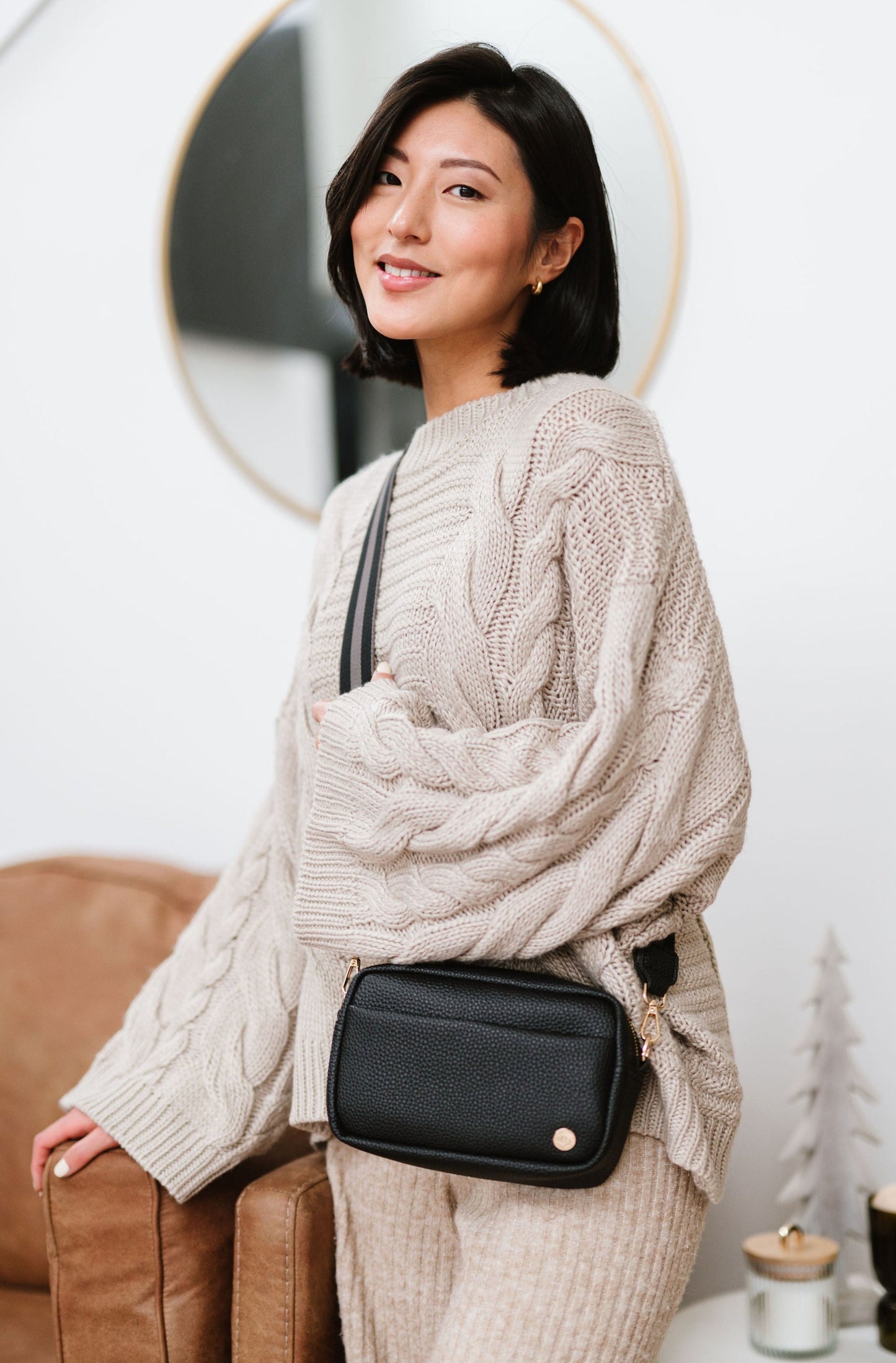 Woman wearing a black Drury Road Willow Vegan Leather Convertible Crossbody Bag in a living room.