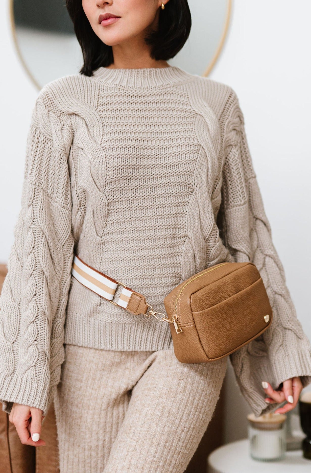 Woman wearing a beige Drury Road Willow Vegan Leather Convertible Crossbody Bag around her waist as a belt bag. 