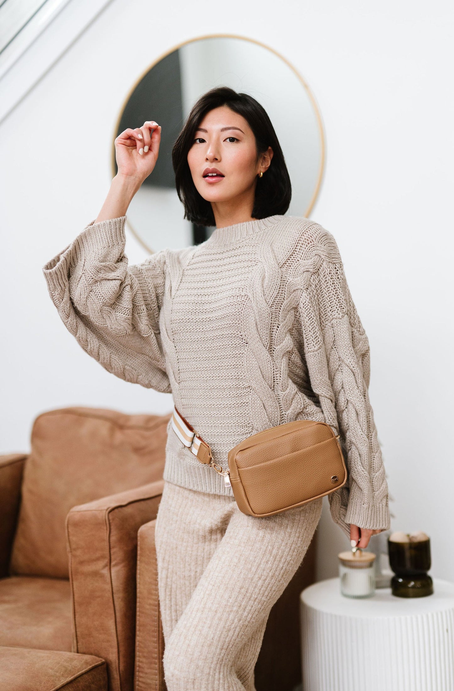 Woman wearing a beige Drury Road Willow Vegan Leather Convertible Crossbody Bag around her waist like belt bag. 